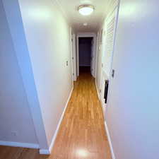 Hall featuring ornamental molding, light wood-style flooring, and a textured ceiling