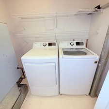 Laundry area with light flooring and independent washer and dryer