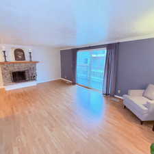 Unfurnished living room featuring light wood-type flooring, a fireplace, a textured ceiling, and floor to ceiling windows