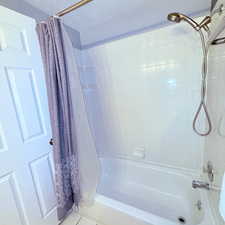 Full bathroom featuring shower / bath combo with shower curtain, tile patterned floors, and a textured ceiling