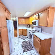 Kitchen with white appliances, light countertops, light tile patterned floors, and a textured ceiling