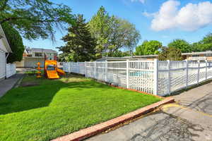 Fenced backyard featuring a community pool and a playground