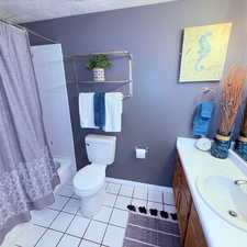 Full bathroom with vanity, shower / bathtub combination with curtain, and light tile patterned flooring