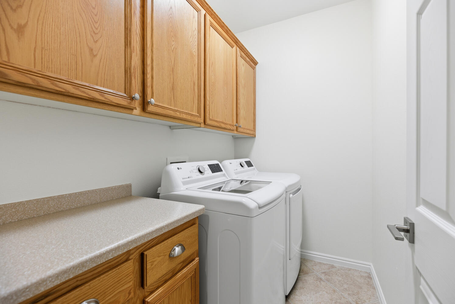 Laundry area with cabinet space, washer and dryer, and light tile patterned floors
