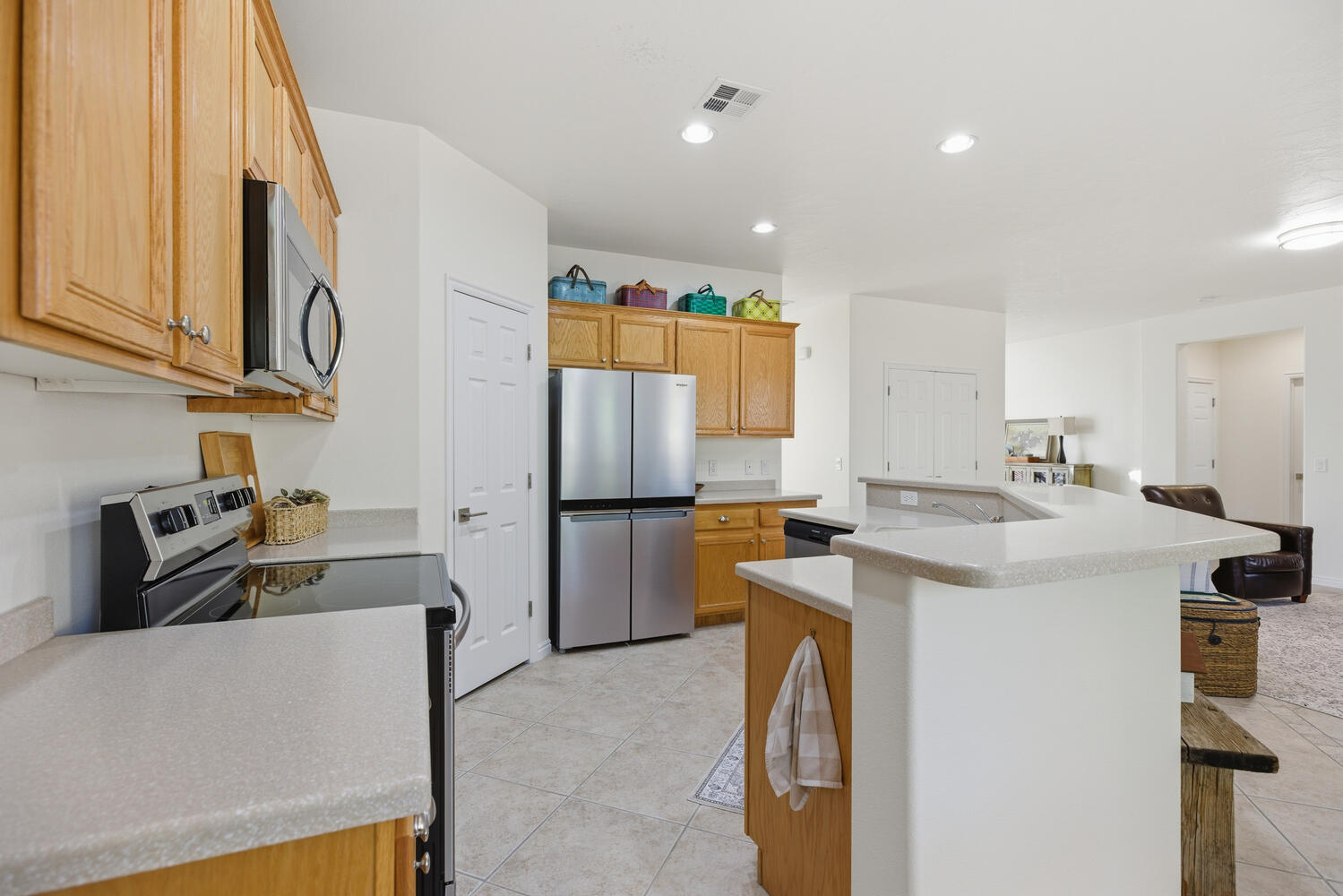 Kitchen featuring stainless steel appliances, an island with sink, light countertops, light tile patterned floors, and recessed lighting