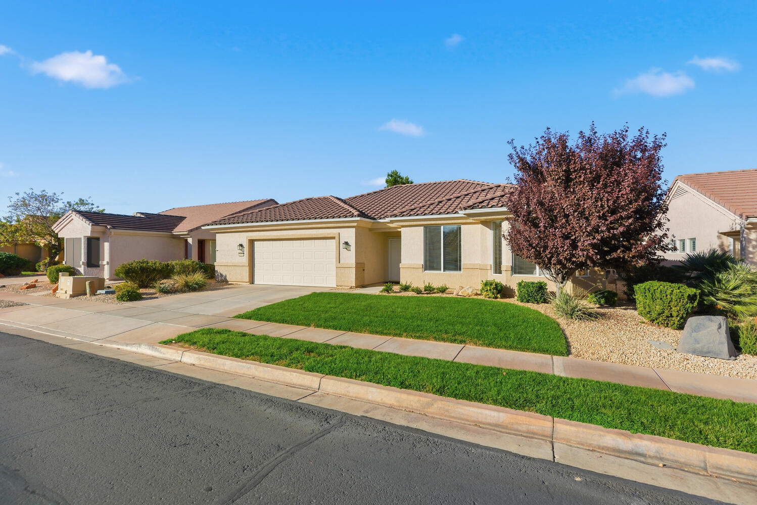 View of front of house with concrete driveway, a tiled roof, a garage, stucco siding, and a front yard