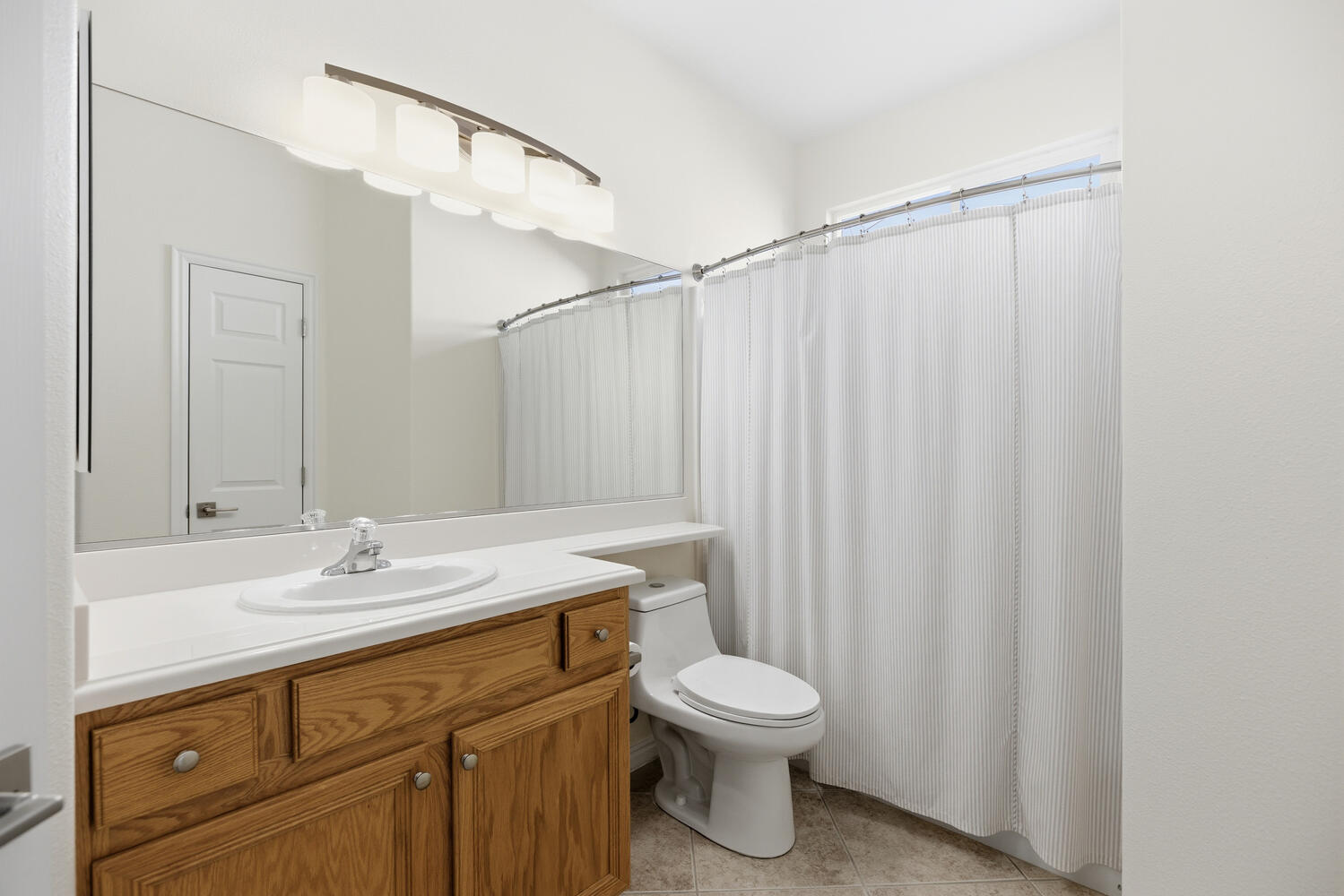Full bath with vanity, curtained shower, and light tile patterned floors