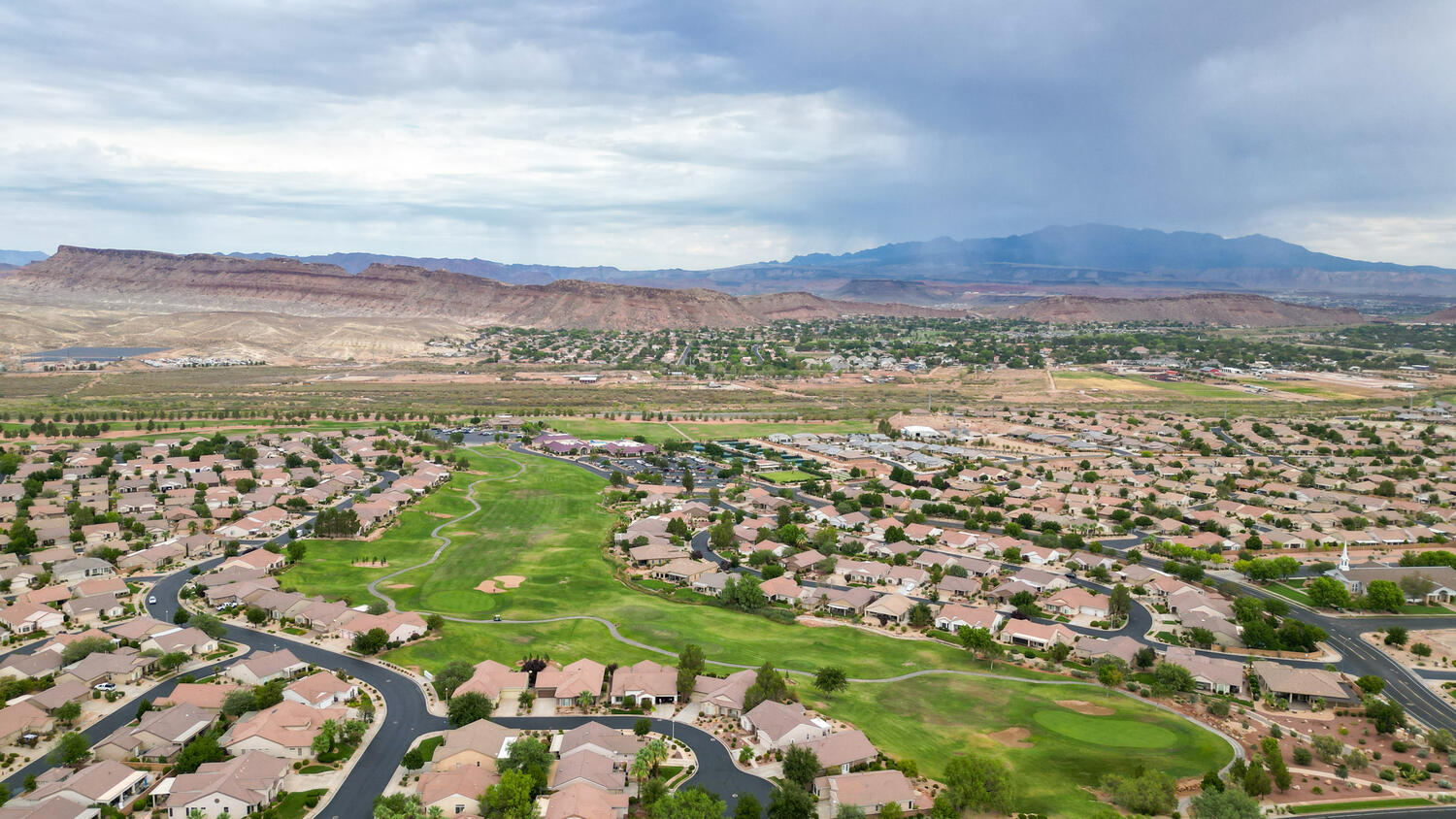 Aerial perspective of suburban area featuring a local golf course and a mountain backdrop