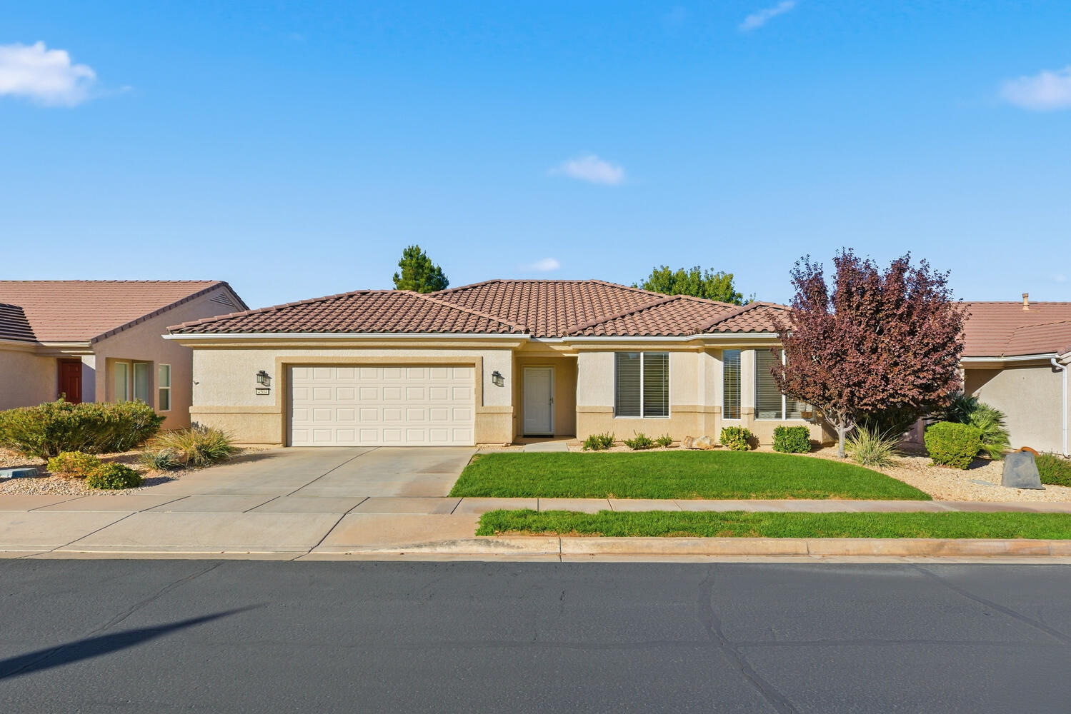 View of front facade featuring a tiled roof, stucco siding, and concrete driveway