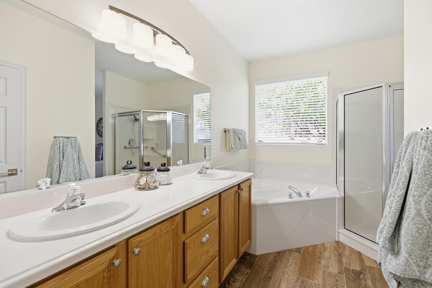 Full bath featuring a stall shower, double vanity, dark wood finished floors, and a bath