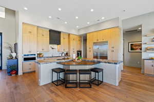 Kitchen with light wood finish cabinets, a breakfast bar, light wood-style floors, and recessed lighting