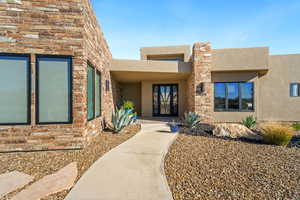 Doorway to property with stucco siding, stone siding, and french doors