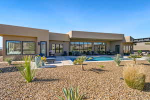 Rear view of property with a patio, stucco siding, and an outdoor pool