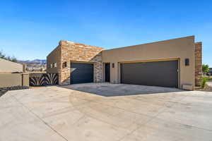 View of front of house with stone siding, driveway, stucco siding, a gate, and a mountain view