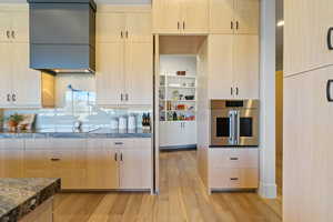 Kitchen featuring light wood finish cabinetry, oven, light wood finished floors, and open shelves