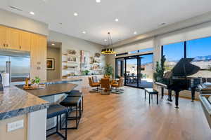 Kitchen with pendant lighting, open shelves, built in fridge, light wood-style flooring, and a kitchen breakfast bar