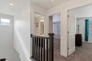 Hallway featuring an upstairs landing, carpet floors, and recessed lighting