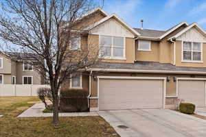 View of front facade with a shingled roof, board and batten siding, driveway, and an attached garage