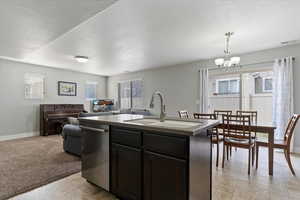 Kitchen featuring a center island with sink, a textured ceiling, dishwasher, and healthy amount of natural light