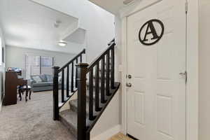 Foyer featuring stairway and carpet