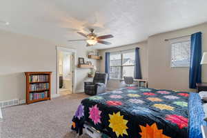 Bedroom with carpet floors, a ceiling fan, ensuite bathroom, and a textured ceiling