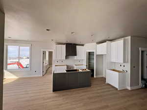 Dual tone kitchen with a center island, two tone color scheme, light wood-type flooring, and recessed lighting