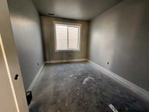 Empty room with unfinished concrete flooring and baseboards