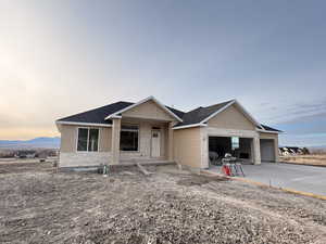 Unfinished property featuring a shingled roof, a garage, driveway, and covered porch