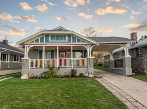 View of front facade with covered porch, a front lawn, concrete driveway, brick siding, and an attached carport