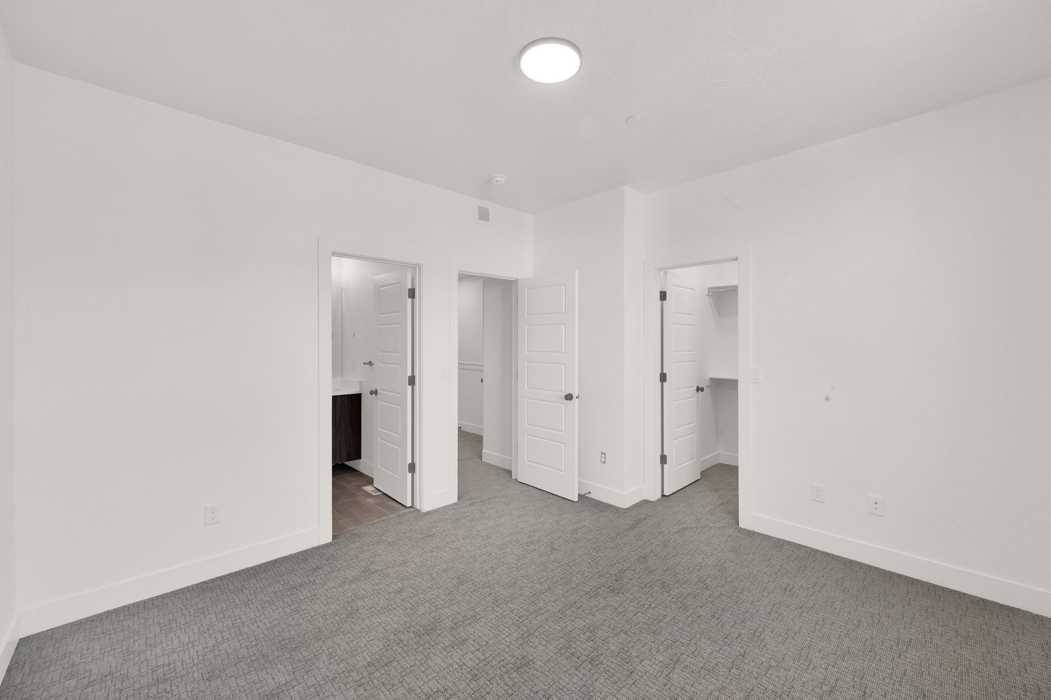 Unfurnished bedroom featuring a walk in closet, carpet floors, and connected bathroom