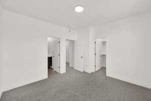 Unfurnished bedroom featuring a walk in closet, carpet floors, and connected bathroom