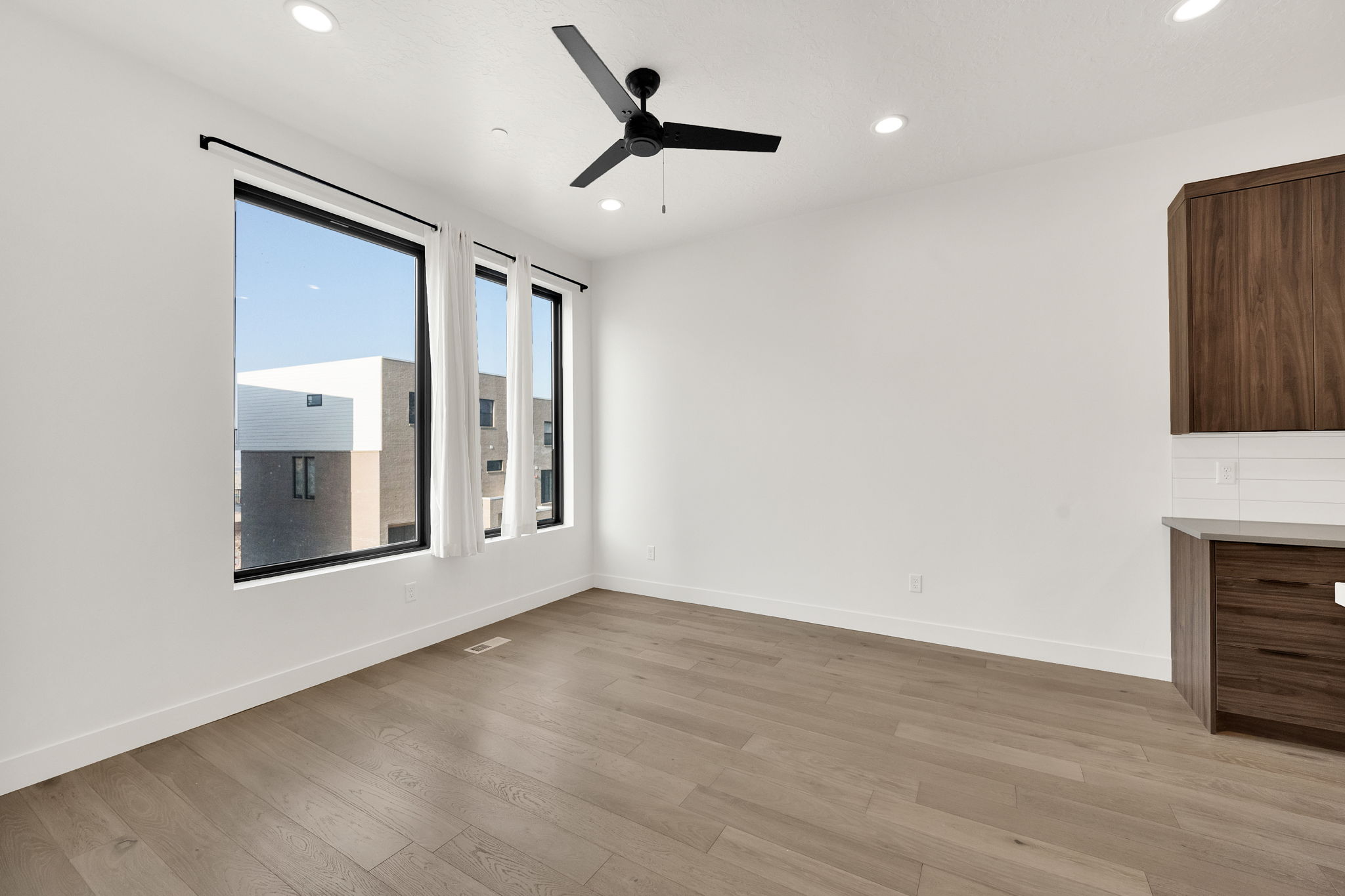 Empty room with a ceiling fan, light wood finished floors, and recessed lighting