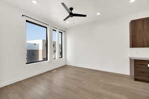Empty room with a ceiling fan, light wood finished floors, and recessed lighting