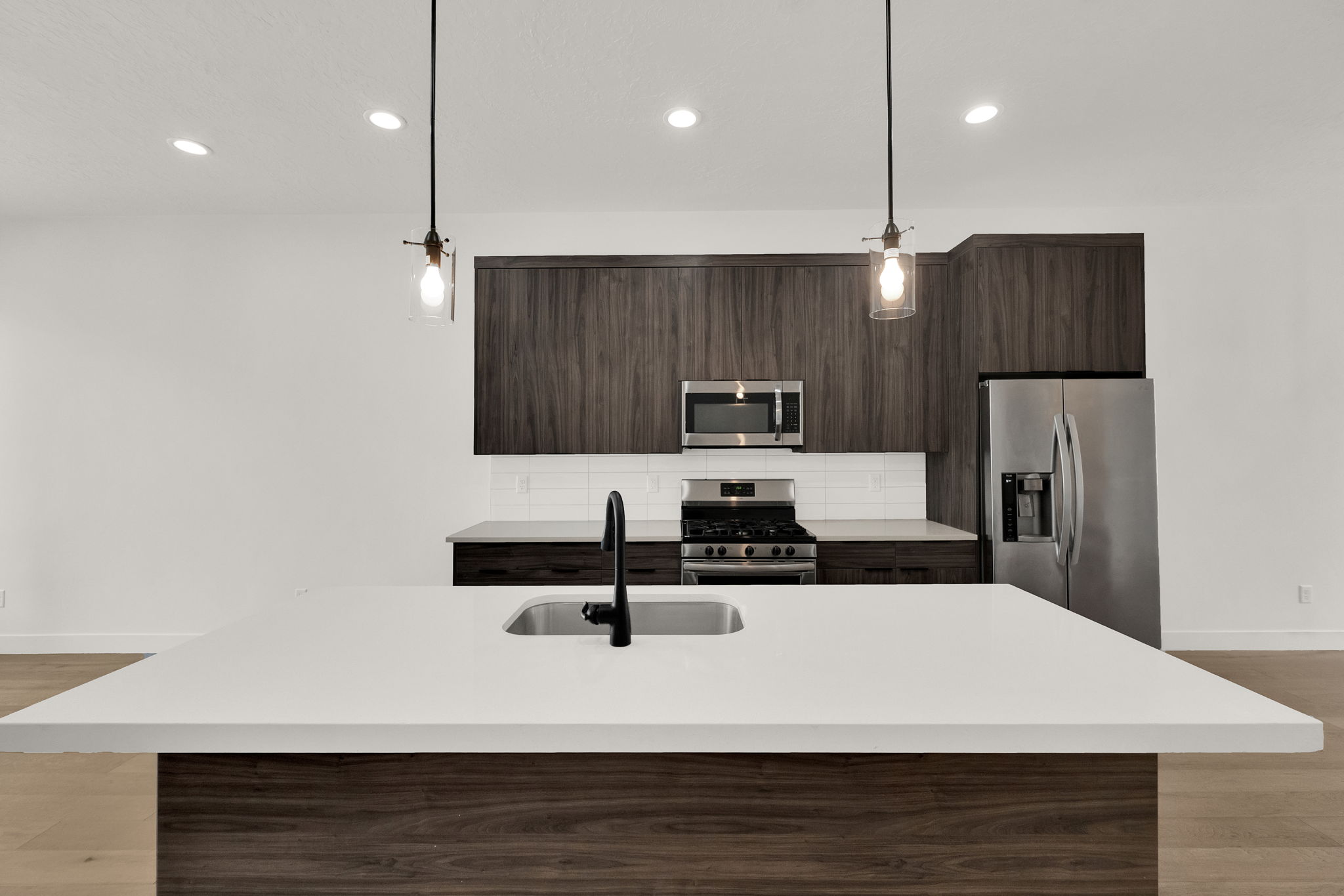Kitchen featuring dark wood finish cabinets, light wood-style floors, stainless steel appliances, and modern cabinets
