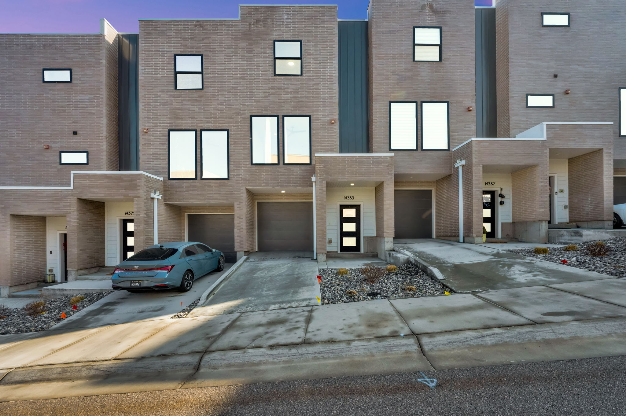 Contemporary home featuring brick siding, an attached garage, and driveway
