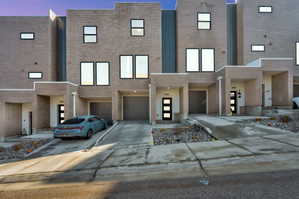 Contemporary home featuring brick siding, an attached garage, and driveway
