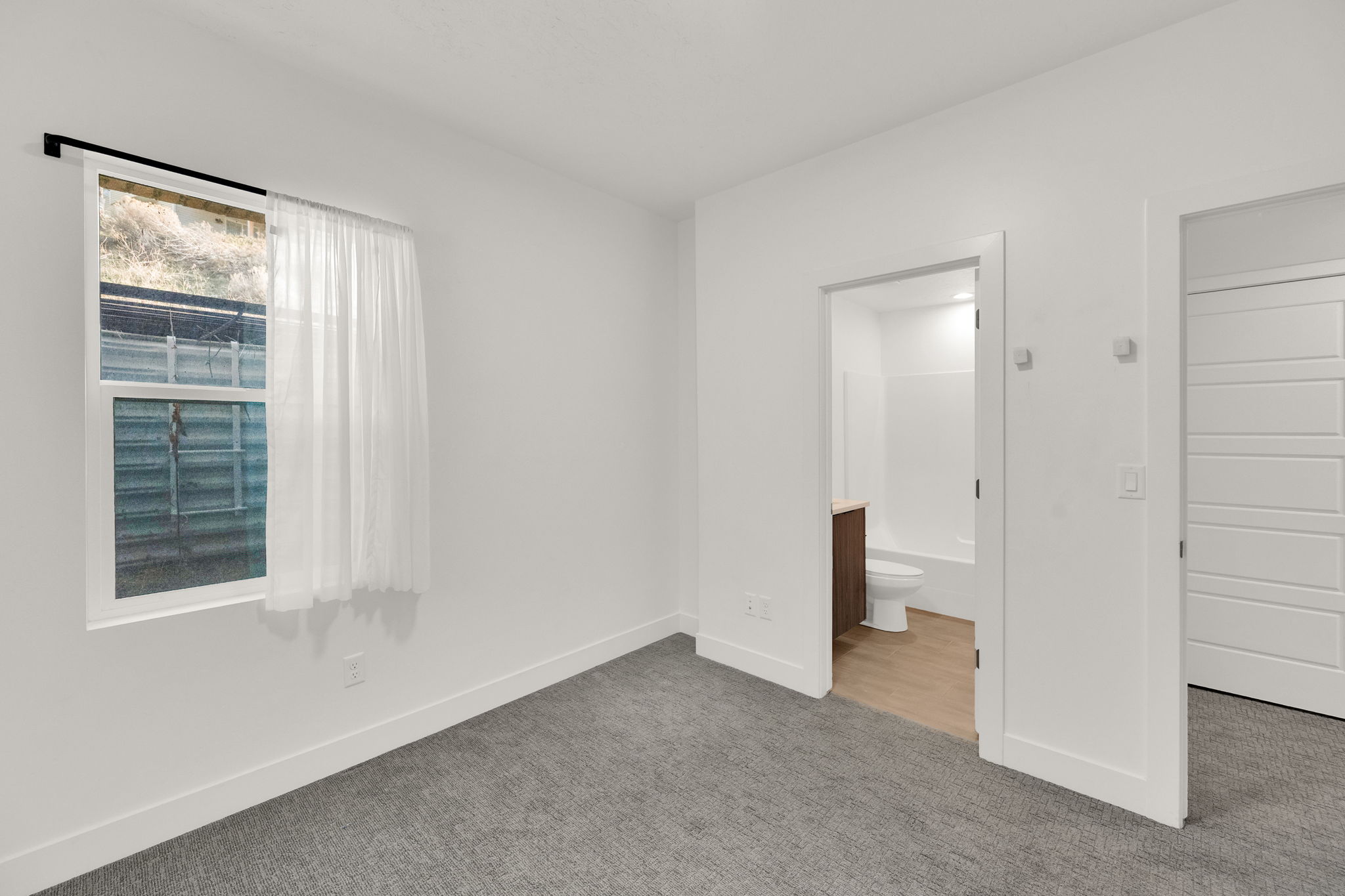 Unfurnished bedroom with carpet and ensuite bathroom