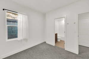 Unfurnished bedroom with carpet and ensuite bathroom