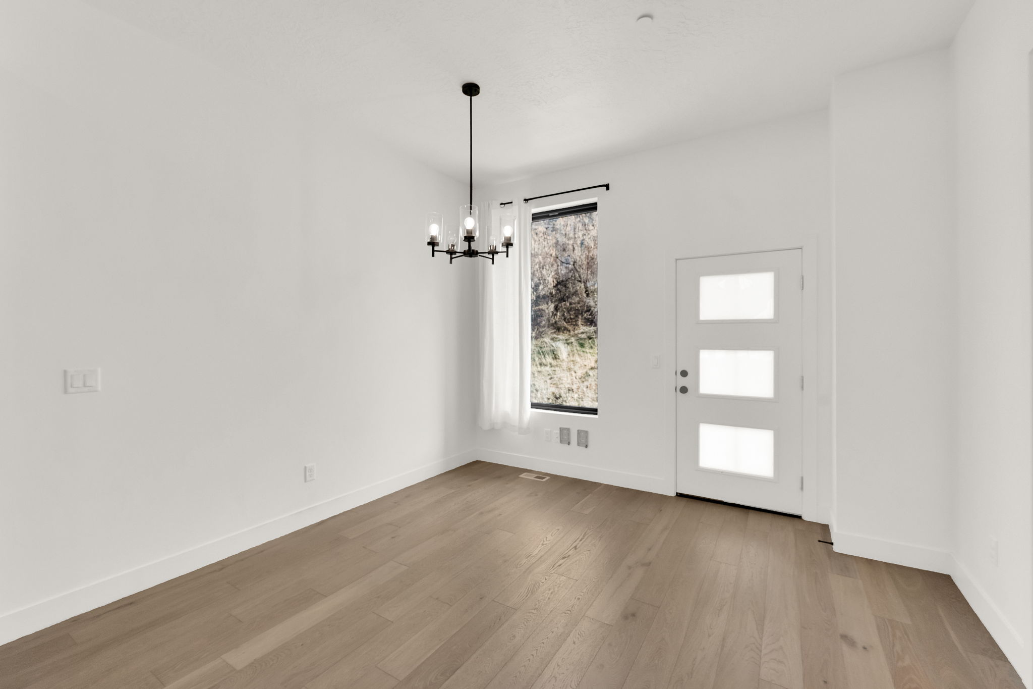 Foyer featuring suspended lighting and light wood-style flooring