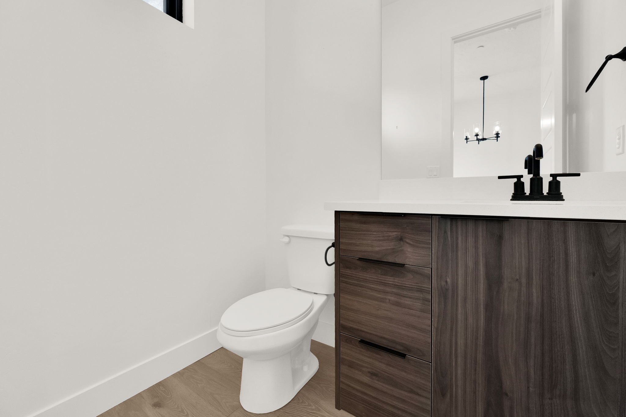 Half bath featuring vanity, light wood-style flooring, and suspended lighting