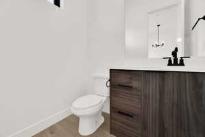 Half bath featuring vanity, light wood-style flooring, and suspended lighting