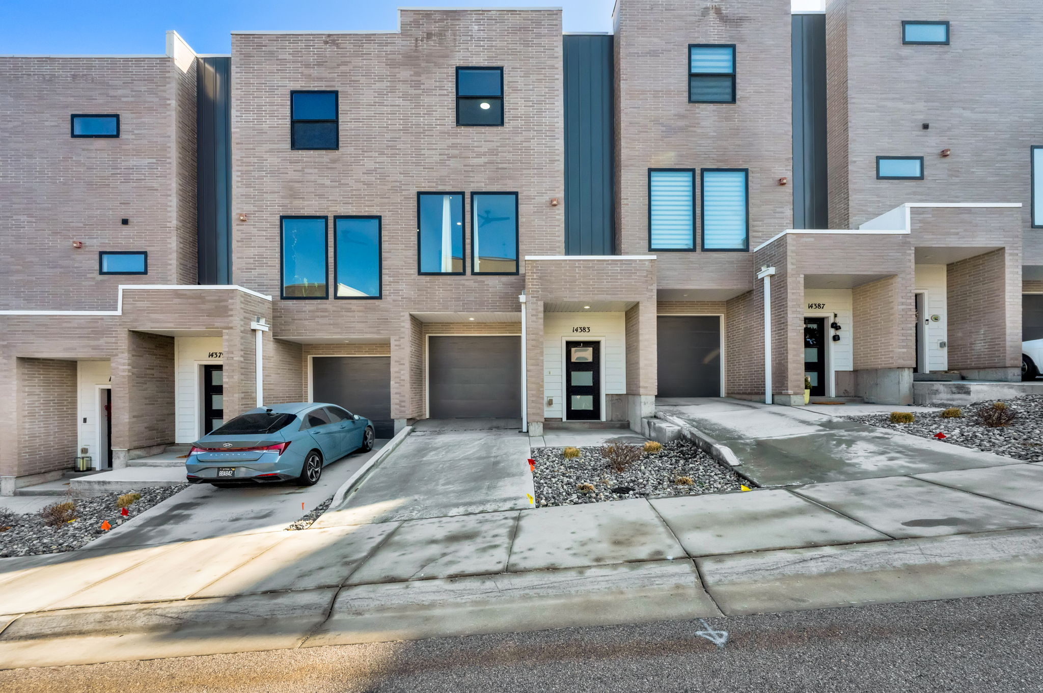 Contemporary home with an attached garage, brick siding, and driveway