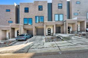 Contemporary home with an attached garage, brick siding, and driveway