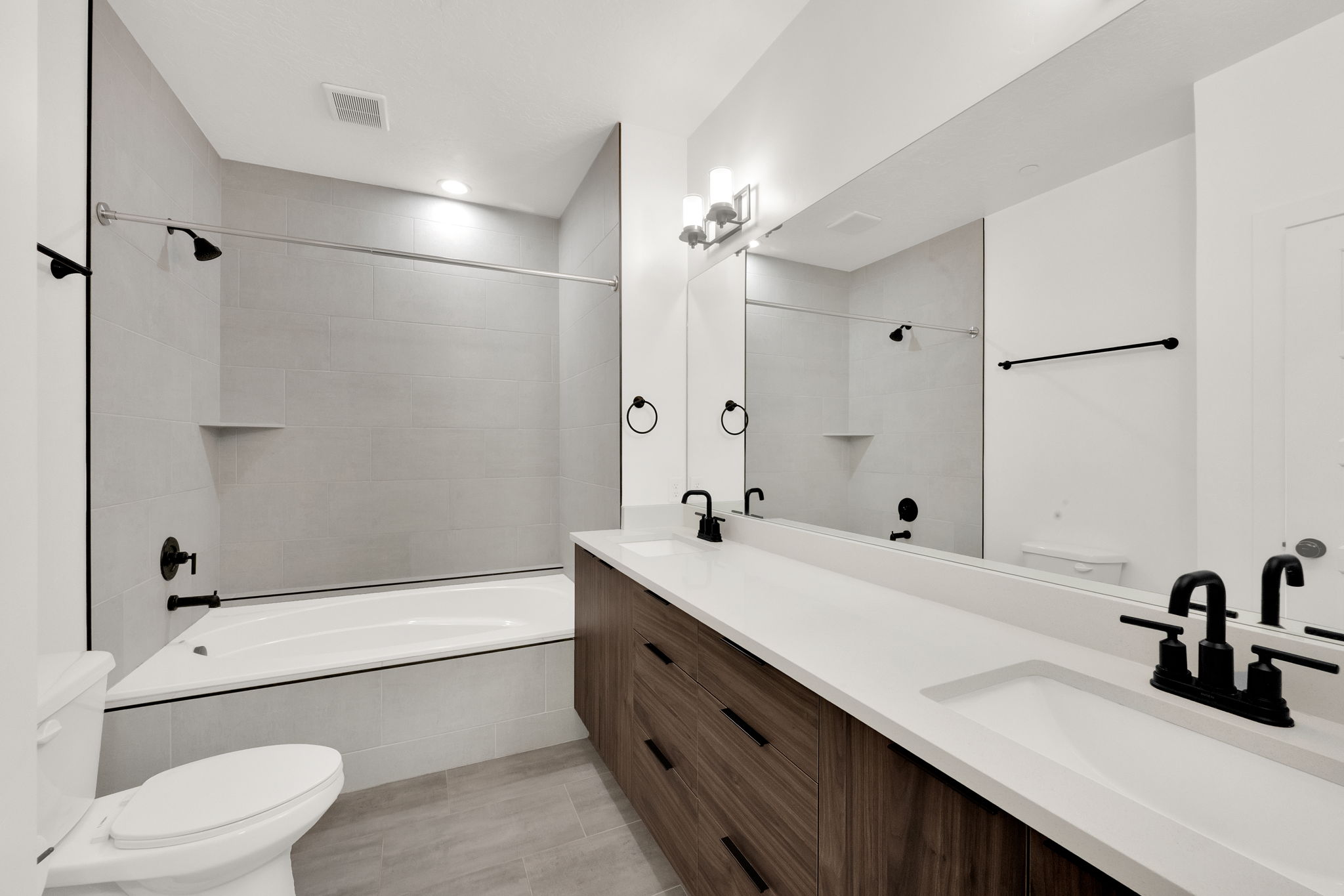 Bathroom with tiled shower / bath combo and double vanity