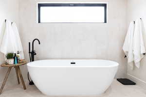 Full bath with a freestanding tub, tile walls, and plenty of natural light