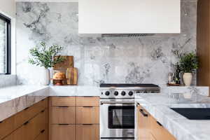 Kitchen with light stone counters, premium stove, decorative backsplash, and modern cabinets