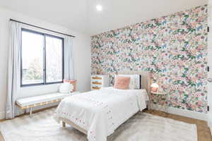 Bedroom with wallpapered walls, wood finished floors, recessed lighting, and an accent wall
