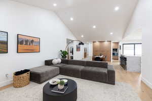 Living area featuring light wood-style flooring, recessed lighting, and vaulted ceiling