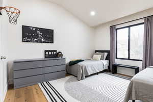 Bedroom featuring wood-type flooring, lofted ceiling, and recessed lighting