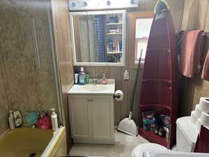 Bathroom with vanity, combined bath / shower with glass door, light tile patterned floors, and wood walls